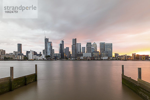 Moderne Skyline von Thames River in der Stadt gegen bewölkten Himmel bei Sonnenuntergang  London  UK