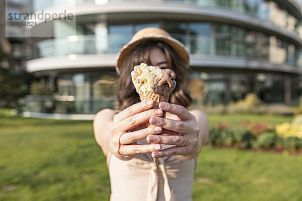 Junge Frau mit Eiscreme in der Hand in einem öffentlichen Park an einem sonnigen Tag