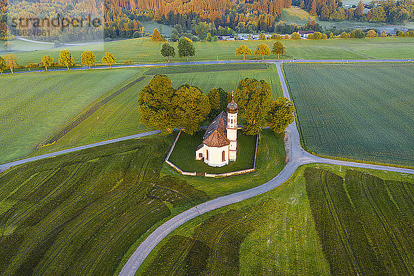 Deutschland  Bayern  Etting  Drohnenansicht der St. Andreas Kirche inmitten grüner Felder in der Morgendämmerung