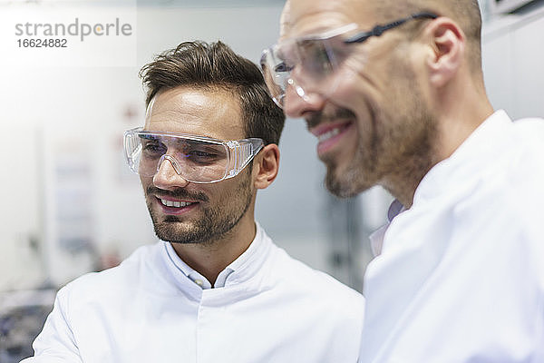 Lächelnde männliche Techniker  die in ein beleuchtetes Labor blicken