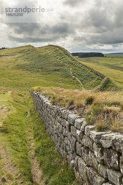 UK  England  Hexham  Wolken über grünen  grasbewachsenen Hügeln und einem Teil des Hadrians Wall