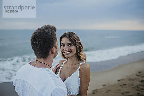 Lächelnde Frau steht mit Mann am Strand