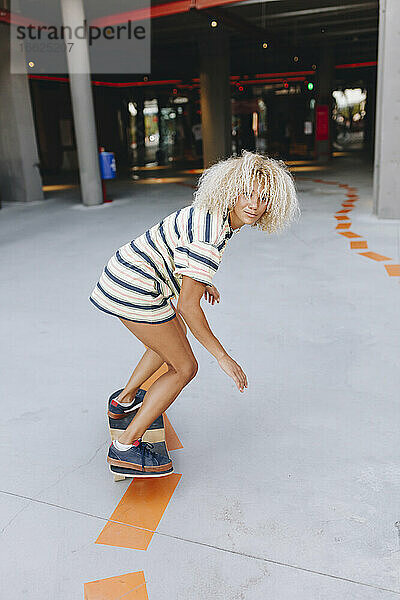 Blonde Afro-Frau beim Skateboarden auf dem Fußweg