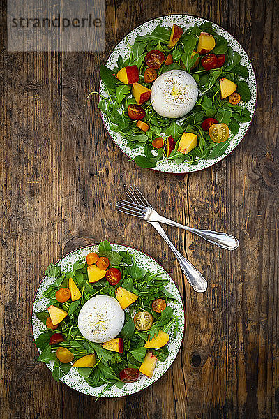 Zwei Teller mit frischem vegetarischem Salat mit Tomaten  Basilikum  Rucola  Nektarinen  Zitronenmelisse und Burrata-Käse