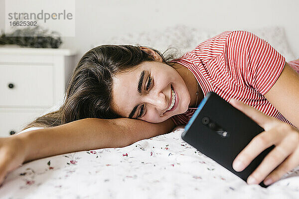 Lächelnde junge Frau  die eine Textnachricht auf einem Smartphone schreibt