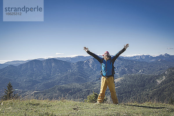 Älterer Mann mit erhobenen Armen auf einem Berg gegen den klaren Himmel stehend  Otscher  Österreich
