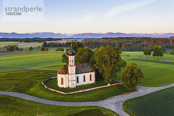 Deutschland  Bayern  Etting  Drohnenansicht der St. Andreas Kirche inmitten grüner Felder in der Morgendämmerung