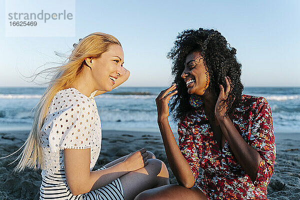 Lachende Freunde  die am Strand miteinander reden