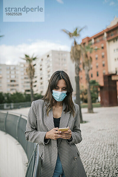 Junge Frau  die in der Stadt steht und mit ihrem Smartphone SMS schreibt