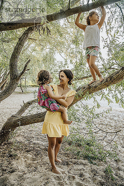 Mutter und Töchter stehen in der Nähe des Weidenbaums