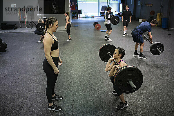 Athleten helfen sich gegenseitig beim Training im Fitnessstudio