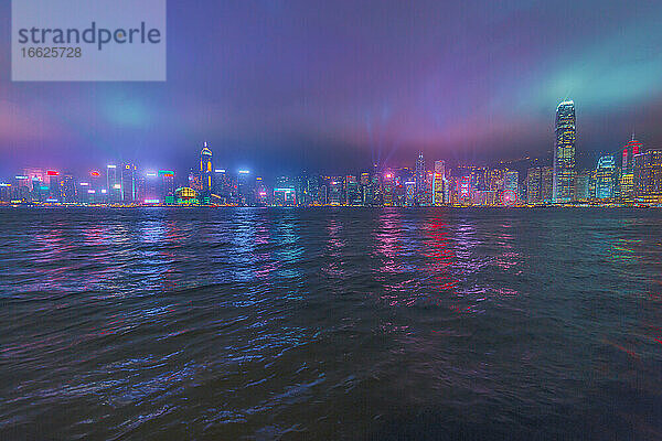 Beleuchtete Gebäude in der Stadt vor dem Meer gegen den Himmel bei Nacht  Hongkong