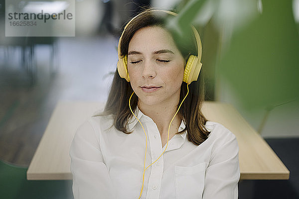 Frau entspannt sich beim Musikhören im Büro
