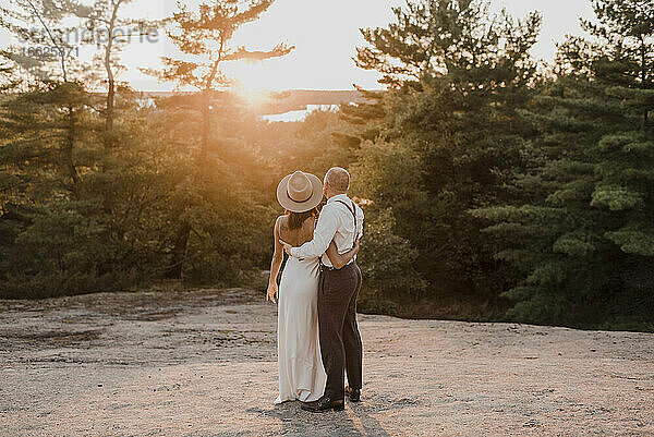 Paar  das gemeinsam den Sonnenuntergang betrachtet  während es auf einem Gehweg im Wald steht