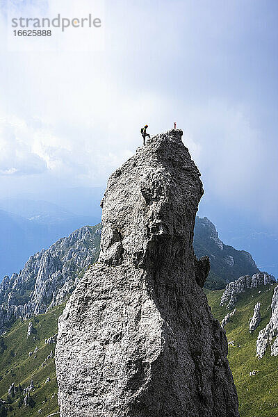 Männlicher Wanderer steht auf dem Gipfel eines Berges gegen den Himmel  Europäische Alpen  Lecco  Italien