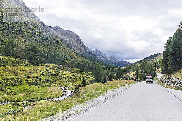 Auto auf der Straße in der Nähe der Bergkette gegen den bewölkten Himmel an einem sonnigen Tag  Sextner Dolomiten  Dolomiten  Südtirol  Italien