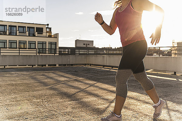 Weibliche Athletin läuft auf einer Gebäudeterrasse in der Stadt