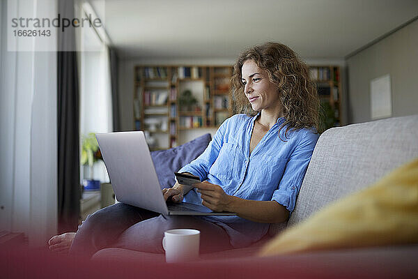 Lächelnde Frau beim Online-Shopping am Laptop zu Hause