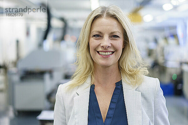 Lächelnd reifen blonden weiblichen professionellen stehend an beleuchteten Industrie