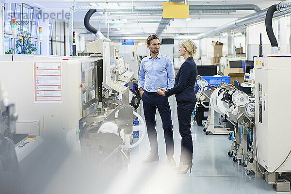 Geschäftsfrau und Geschäftsmann diskutieren über Maschinen in der Beleuchtungsindustrie
