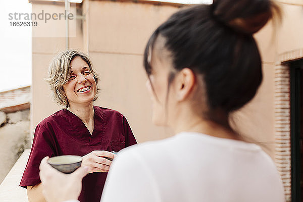 Lächelnde Physiotherapeutin im Gespräch mit einer Frau auf dem Dach