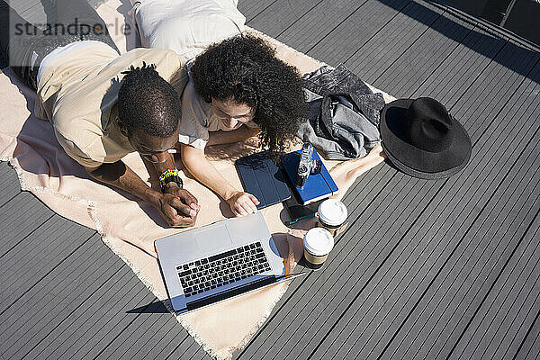 Mann und Frau benutzen Laptop  während sie auf dem Brückenweg in der Stadt liegen