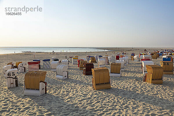Stühle mit Kapuze am Strand gegen den Himmel bei Sonnenuntergang