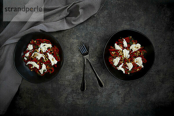 Zwei Schalen vegetarischer Salat mit roter Paprika  Mozzarella  gerösteten Pinienkernen  Petersilie und Schnittlauch