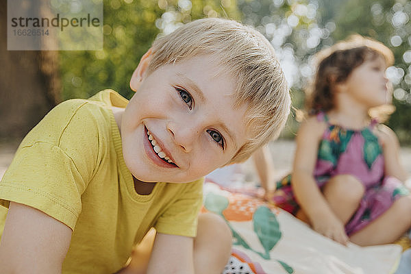 Niedliche Kinder sitzen am Strand an einem sonnigen Tag