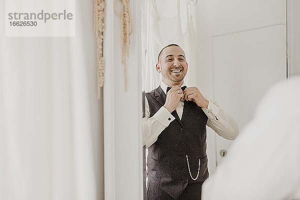 Bräutigam richtet seine Verbeugung aus  während er sich zu Hause im Spiegel betrachtet