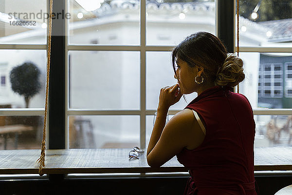 Junge Frau sitzt an der Bar und wartet