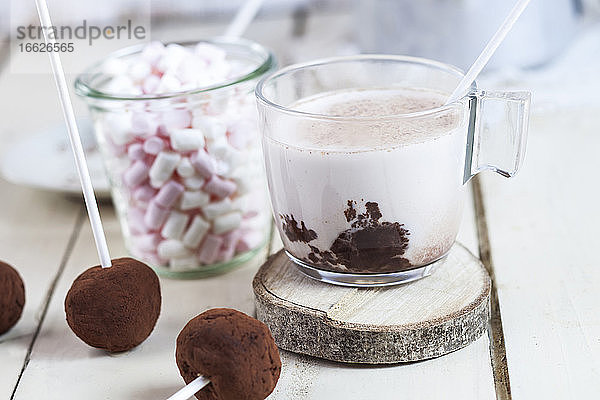Nahaufnahme von heißer Schokolade mit Trüffel-Lutschern und Marshmallows auf dem Tisch zu Hause