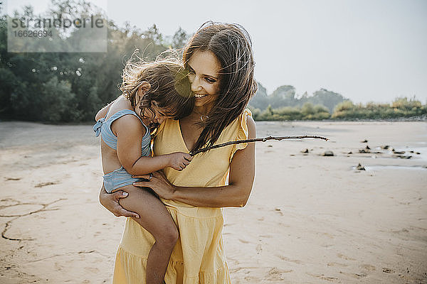Glückliche Mutter hält ihre Tochter am Strand in den Armen