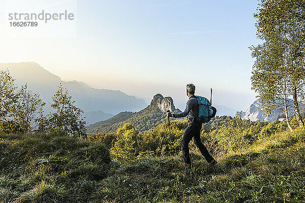 Männlicher Wanderer  der bei Sonnenaufgang auf einem Berg gegen den Himmel läuft  Orobie  Lecco  Italien