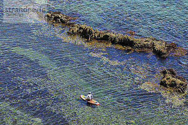 Luftaufnahme von Frau Paddleboarding im klaren Wasser der Lukin Bucht