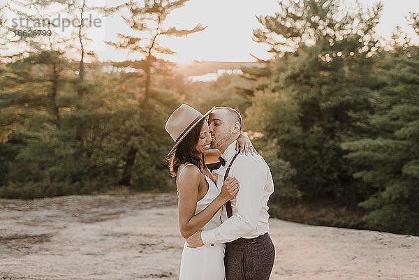 Paar küsst sich bei Sonnenuntergang auf einem Gehweg im Wald