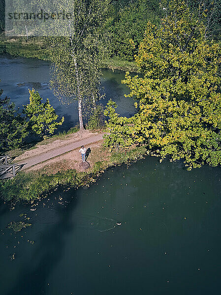 Drohnenaufnahme einer am Teich stehenden Frau