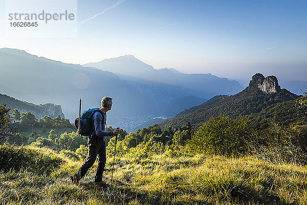 Männlicher Wanderer mit Stock auf einem Berg gegen den Himmel bei Sonnenaufgang  Orobie  Lecco  Italien