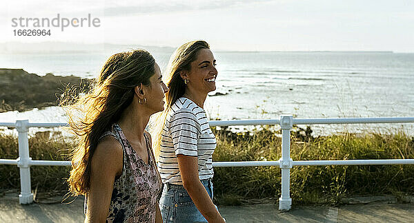 Lächelnde junge Frauen auf dem Fußweg an einem sonnigen Tag