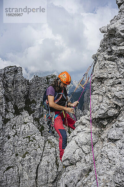 Männlicher Bergsteiger mit Seil  der auf einem Berg balanciert  Europäische Alpen  Lecco  Italien