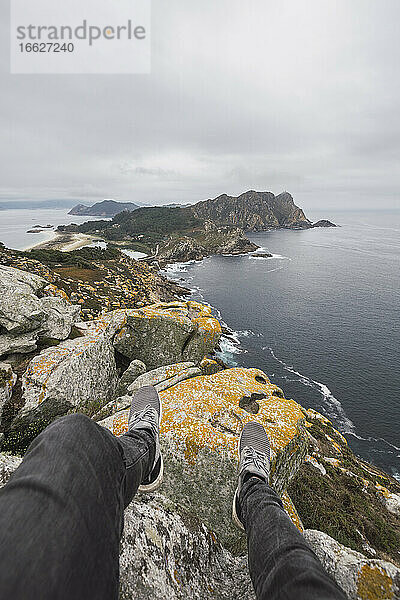 Tiefschnitt eines jungen männlichen Touristen über einer Felsformation vor bewölktem Himmel  Cíes-Inseln  Vigo  Provinz Pontevedra  Galicien  Spanien