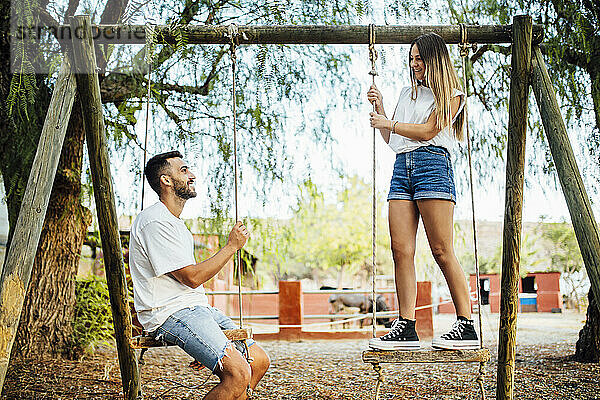 Junges Paar verbringt Zeit auf Schaukeln in einem öffentlichen Park