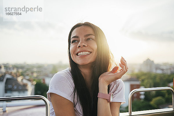 Glückliche Frau  die das Riesenrad genießt  während sie bei Sonnenuntergang in den Himmel schaut