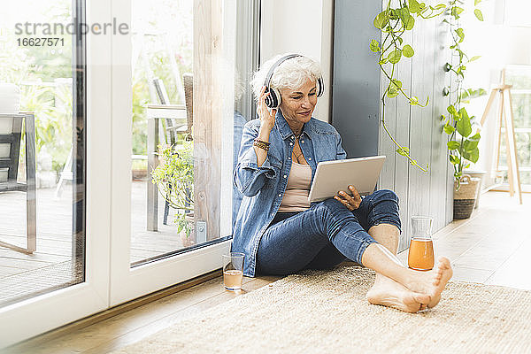 Reife Frau hört Musik und arbeitet an einem digitalen Tablet