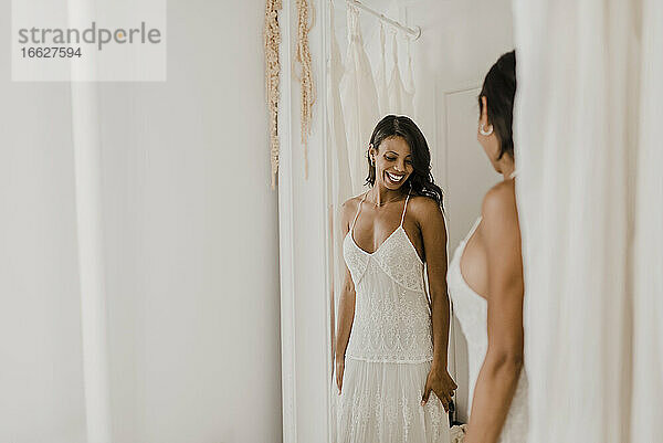 Lächelnde Braut schaut in den Spiegel  während sie zu Hause steht