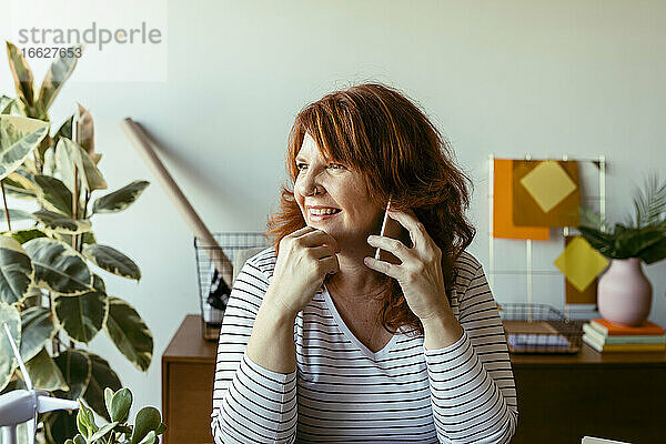 Lächelnde Frau  die zu Hause am Telefon sitzt