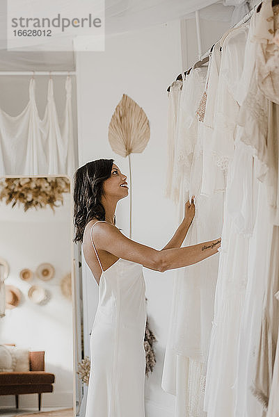 Junge Braut bewundert Kleid  während sie zu Hause steht