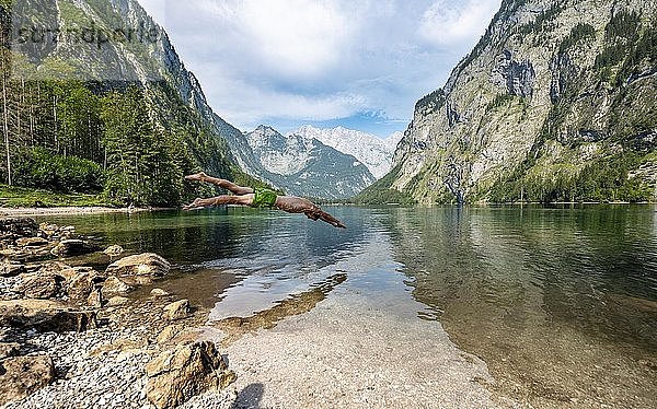 Junger Mann springt in See  badet in Bergsee  Berge spiegeln sich im Obersee  hinten Watzmann  Salet am Königssee  Nationalpark Berchtesgaden  Berchtesgadener Land  Oberbayern  Bayern  Deutschland  Europa