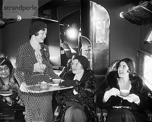 Vereinigte Staaten  10. Januar 1931.
Eine Stewardess der Eastern Air Transport serviert Tee für die Passagiere  denen zu ihrer Unterhaltung auch Zigaretten und Bridge-Spiele zur Verfügung stehen.