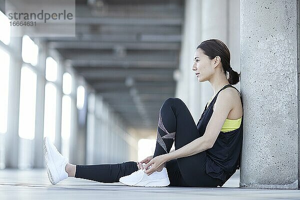 Junge japanische Frau  die beim Joggen eine Pause macht